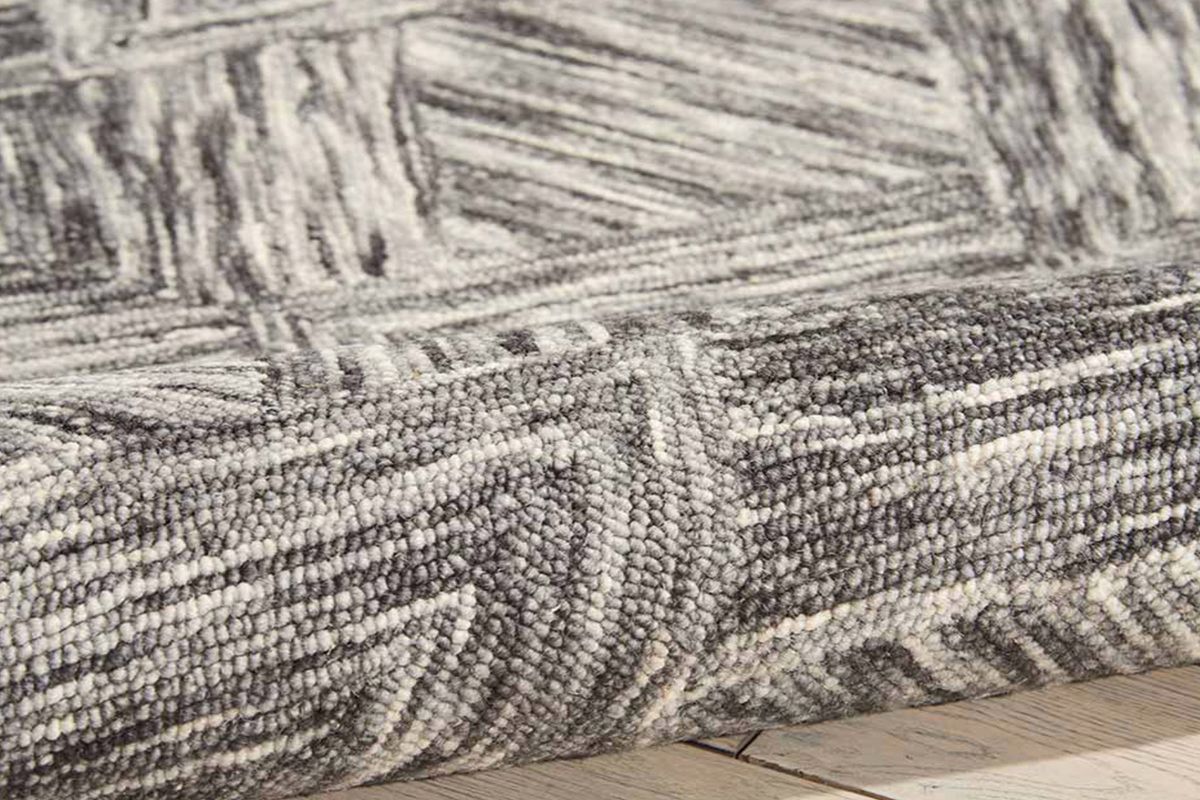An area rug in mixed gray colors that's been folded over.