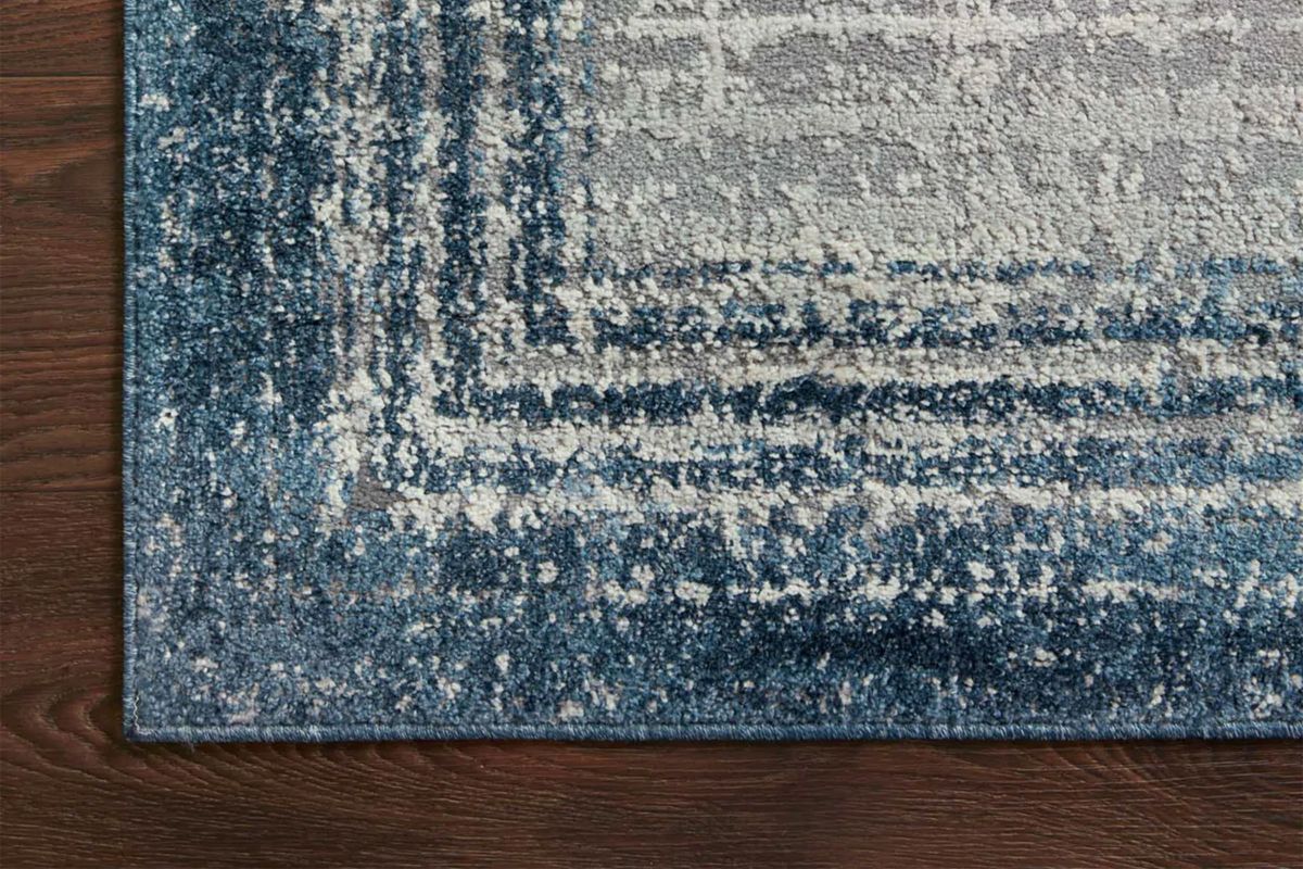 The corner of a blue striped rug on a dark brown wooden floor.