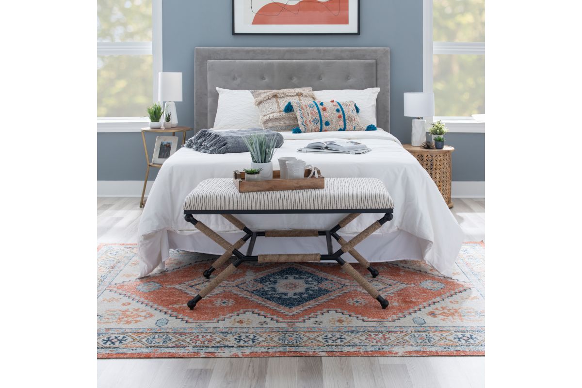 A short table with a breakfast tray stop it sitting at the end of a queen bed.