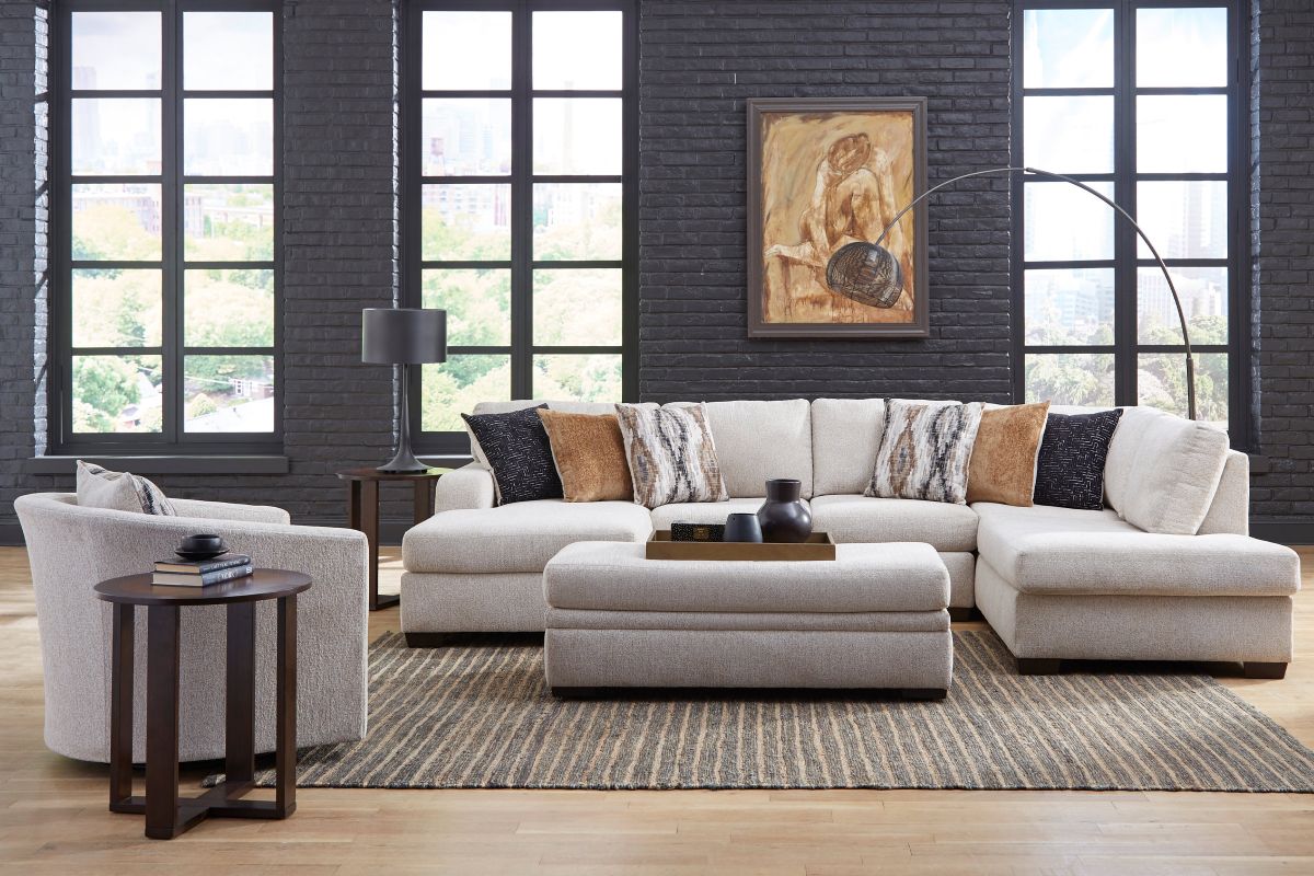 A living room set of furniture in light gray including a sectional sofa, an accent chair, and a dark brown wooden table.